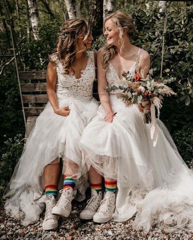 Na een verloving van anderhalf jaar zijn Erica en Laura in het huwelijksbootje gestapt. Het resultaat: een vrolijke maar intieme bruiloft, met regenboogkleuren die steeds subtiel voorbijkwamen. Voor alle mooie plaatjes moet je even naar de link in bio🌈.⁠
⁠
Leveranciers⁠
Fotograaf @louiseboonstoppelfotografie⁠
Second shooter voorbereidingen Laura @authenticwildstories ⁠
Locatie @landtgoed⁠
Bruidskapsel @ruth_hairandmakeup ⁠
Make-up @spot.schoonheidssalon ⁠
Bloemen @via.flora ⁠
Jurken @honybruidsmode ⁠
Ringen @bobiniroots ⁠
BABS @alice_in_weddingland ⁠
⁠
#girlsofhonour #trouwen #bruiloft #WijGaanTrouwen #wedding #WeddingInspiration #BruiloftInspiratie #BruiloftBlogger #TrouwenIn2022 #trouwblog #trouwplannen #huwelijk #WijZijnVerloofd #ISaidYes #BrideToBe2022 #WeddingHacks #DutchModernBrides #ModerneBruid #ModernBride #LittleThingsTheory #WeddingDetails⁠
⁠
ID: Twee bruiden zitten op een hangbankje naast elkaar. Ze dragen beiden hun haren half opgestoken, hebben allebei lange witte trouwjurken met V-hals aan en dragen witte sneakers met regenboogsokken.
